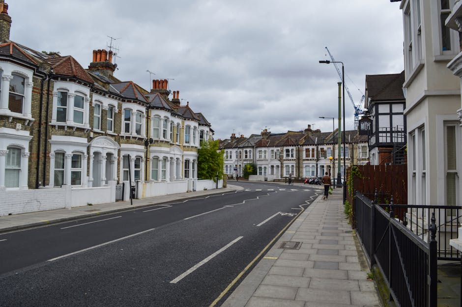 A quiet residential street in Tottenham N17 lined with Victorian-style terraced houses, featuring bay windows, decorative brickwork, and chimneys. The pavement on the right side has a black metal fenc